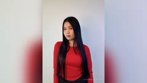 Young woman in a red long-sleeve top posing with a calm expression against a plain white background.