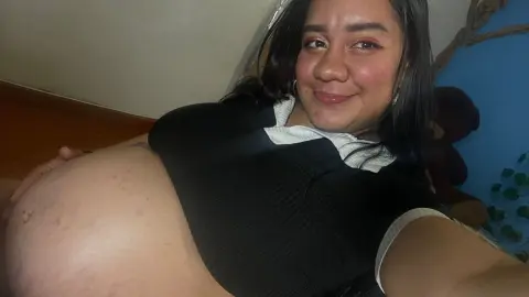Smiling pregnant woman in a black top relaxing at home with a joyful mood.