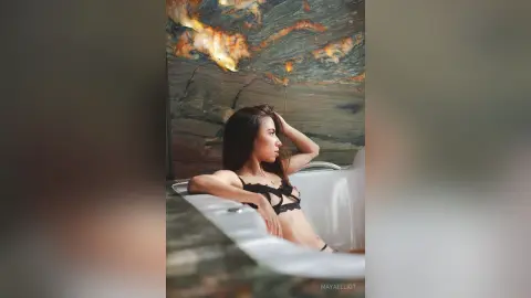 Elegant woman in black lace lingerie relaxing in a luxury marble bathtub for a moody lifestyle aesthetic.