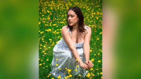IsabellaYork — Young woman in a white floral sundress sitting peacefully in a sunny yellow wildflower meadow.
