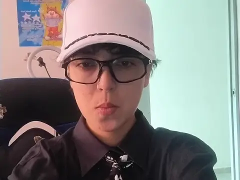 Young person with glasses and white cap wearing a black shirt in a bright indoor setting.