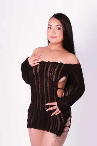 Young woman in a black off-the-shoulder knit sweater dress posing against a white background.