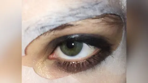 Close-up of a woman's eye featuring dramatic dark smoky eyeshadow and long natural eyelashes.