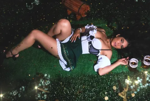 Woman in traditional dirndl outfit lying on green grass at a festive night garden party.