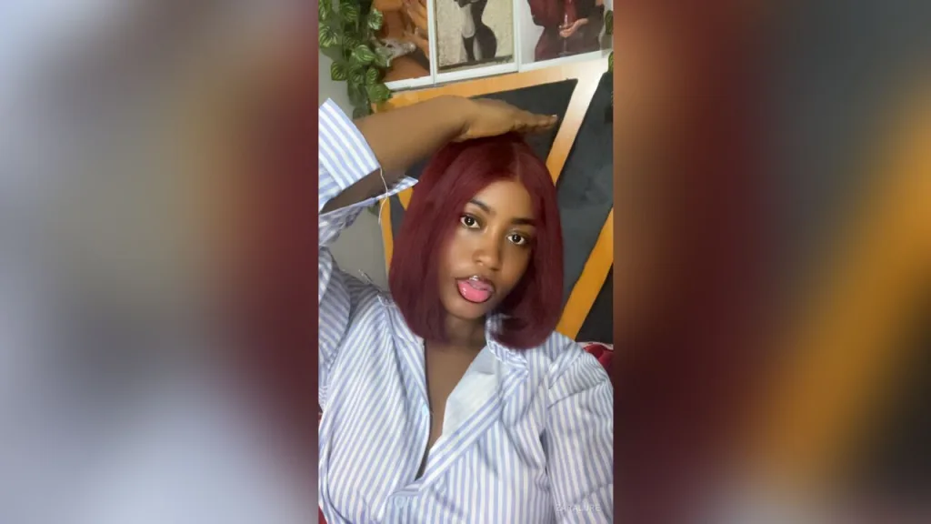 ZaraLure — ZaraLure sticks her tongue out while wearing an unbuttoned blue and white striped shirt.