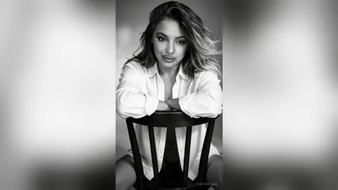 DorothyLake — DorothyLake leans forward over a black chair wearing an unbuttoned white shirt.