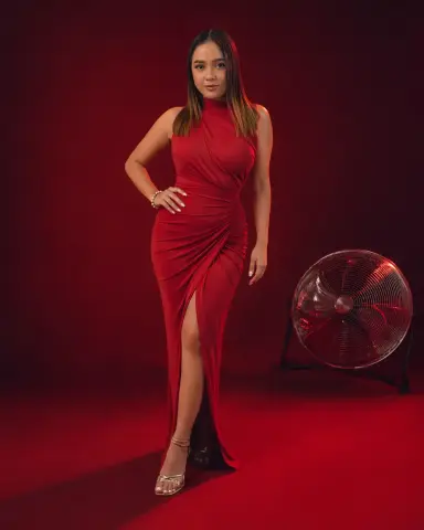 Elegant woman in a red halter maxi dress posing against a bold red studio background.