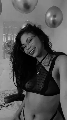 Smiling young woman in black lace lingerie posing in a room decorated with silver balloons.