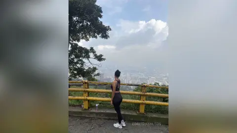 LoreyHamilton — Athletic woman in black gym wear overlooking a misty cityscape from a scenic mountain lookout.