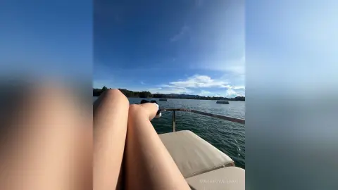 Relaxed person relaxing on a boat deck overlooking a calm blue ocean under a sunny sky.