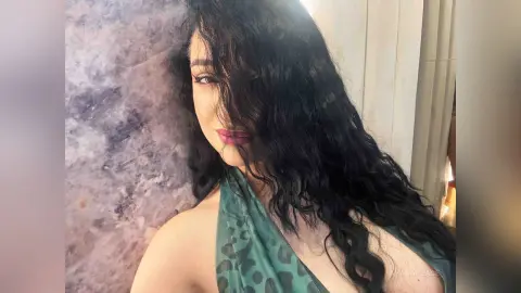 Glamorous woman with long wavy hair wearing a green leopard print halter top against a marble wall.
