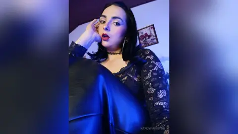 Glamorous woman in a black lace top and leather pants posing with moody blue lighting.
