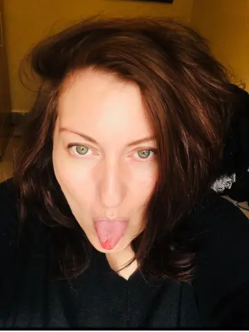 Curvygirllouisa looks at the camera with her tongue sticking out, wearing a black sweater and showing her brown hair.