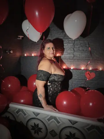 LaurenRiley poses in black lace lingerie, surrounded by red and white heart-shaped balloons and lit candles.