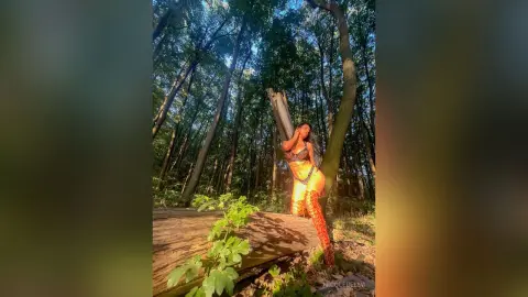 NicoleBella poses in a forest setting wearing a black lace bra and matching lace undies.