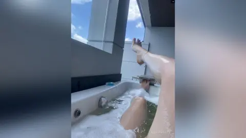 EllieFrosty relaxes in a white bathtub filled with soapy bubbles, showing her legs extended upward toward the sky.