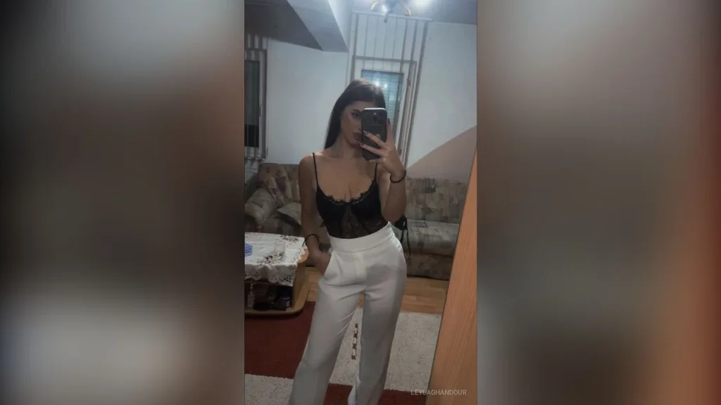 LeylaGhandour sits on a beige couch wearing a black strapless top.