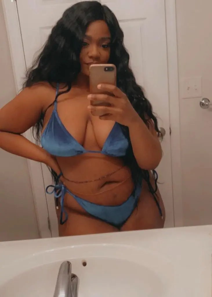 AlexisBanks143 poses with dark lipstick and wavy black hair, looking into the camera.
