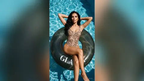 Glamorous woman in a patterned gold swimsuit relaxing on a black floatie in a sparkling blue swimming pool.