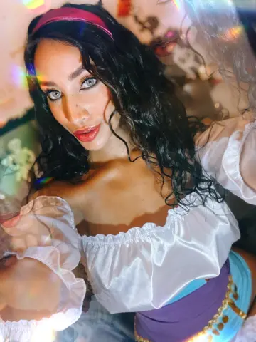 Beautiful woman with wavy dark hair in a white off-the-shoulder blouse enjoying dreamy, colorful lighting.