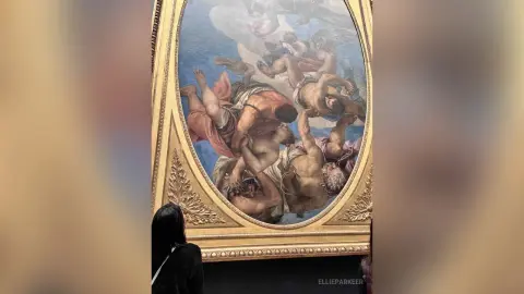 Classical oil painting of mythological figures in a gold frame displayed in a museum gallery.