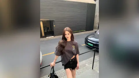 Young woman in a charcoal oversized graphic t-shirt and denim shorts standing on a city street.
