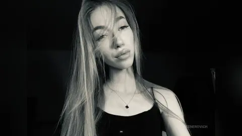 NikkiTenerovich poses for a close-up portrait wearing a black tank top and a small necklace.