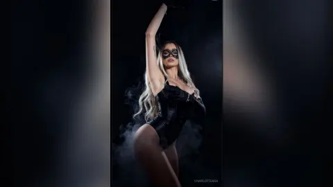 Mysterious woman in a black lace bodysuit and mask posing amidst dark cinematic smoke.
