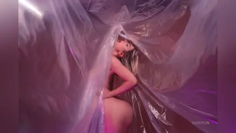 Blonde woman in ethereal lighting draped in translucent pink plastic fabric for a dreamy, artistic mood.