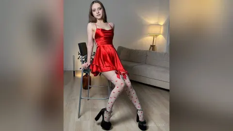 MiaAngelove — MiaAngelove sits on a chair wearing a short red satin dress and white heart-patterned thigh-high stockings.