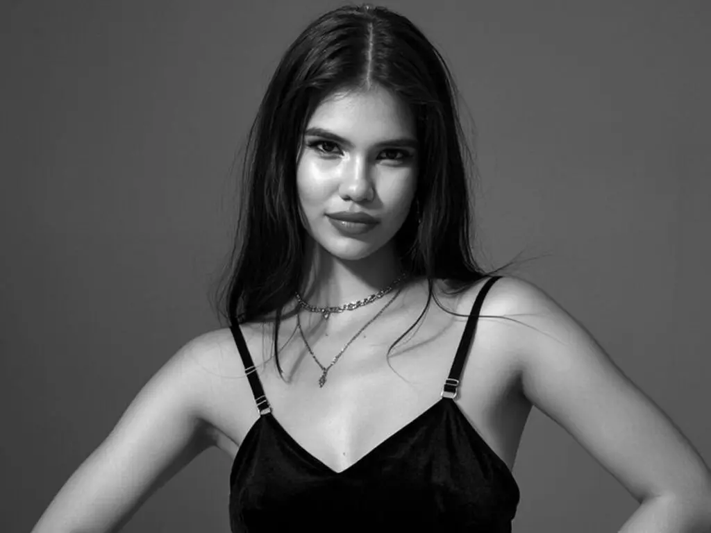 Portrait of a young woman in a black velvet camisole against a minimalist studio background in black and white.