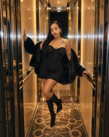 Elegant woman in a black sequin mini dress and faux fur coat posing in a luxury gold elevator.