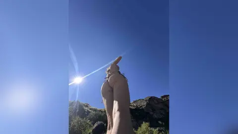 Young woman in a bikini relaxing under a bright sunny sky in a scenic mountain landscape.