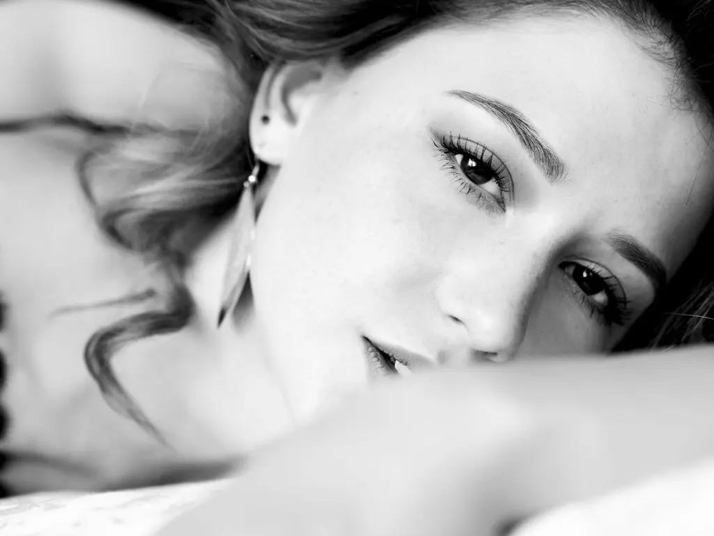 RitaMoonllight poses close-up with her long wavy hair and dark eyes, looking directly at the camera in this black and white headshot.