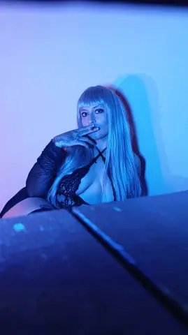Moody portrait of a blonde woman in black lace lingerie under cool blue neon lighting.