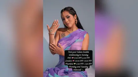 Elegant woman in purple silk saree and gold jewelry posing gracefully against a soft studio background.