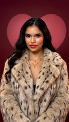 Beautiful woman in a stylish leopard print faux fur coat posing against a romantic red heart background.