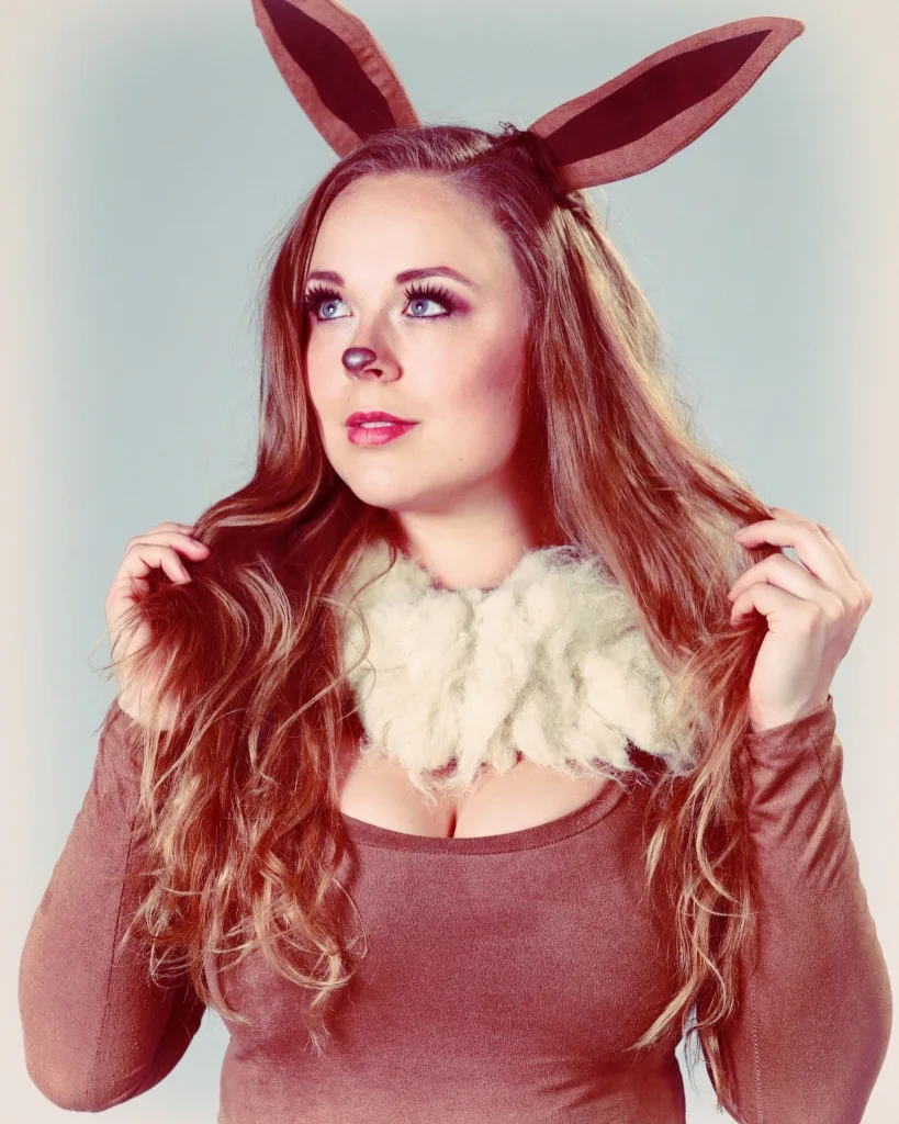 AussieCosplay looks at the camera with a soft smile, showing her face and light blonde hair against a plain background.
