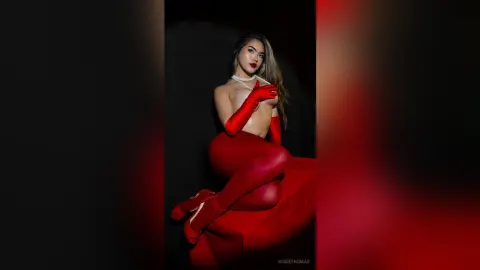 RosieThomas — Glamorous woman in red bodysuit and gloves posing elegantly against a dark studio background.