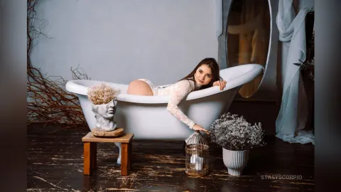 StasyScorpio — StasyScorpio reclines in a white clawfoot bathtub wearing white lace lingerie.