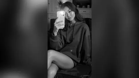 LeahReel — Young woman in a cozy hoodie taking a moody black and white mirror selfie at home.
