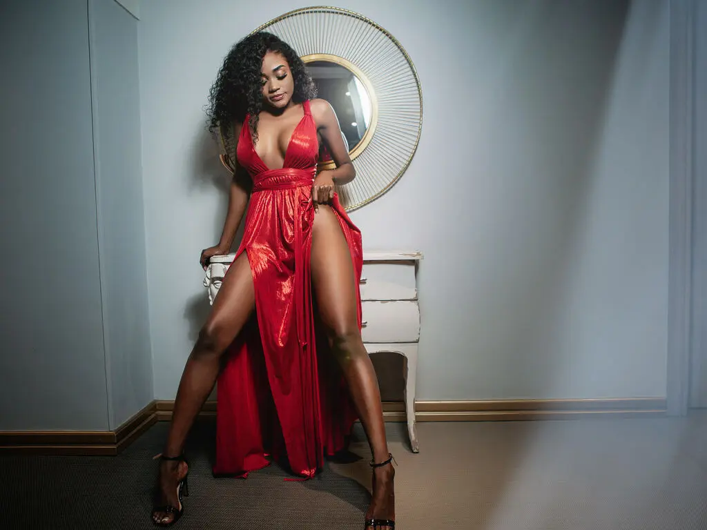 Elegant woman in a glamorous red satin slit dress posing in a modern minimalist room.