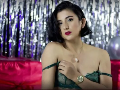 Glamorous woman in green lace lingerie posing against a silver tinsel backdrop for a festive celebration.