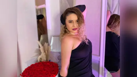Blonde woman in a black dress posing in a mirror with red roses for a glamorous lifestyle mood.