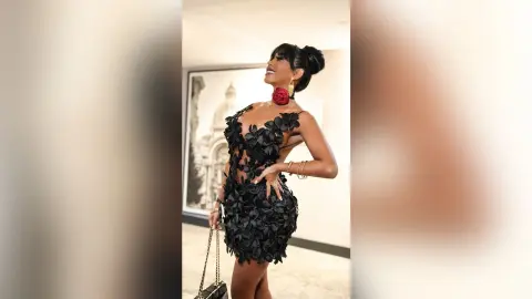 Dolce poses in a black floral lace mini dress with her hand on her hip, wearing large red earrings and her hair in a high bun.