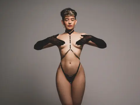 Elegant woman in black lace lingerie and sheer gloves posing against a neutral studio background.