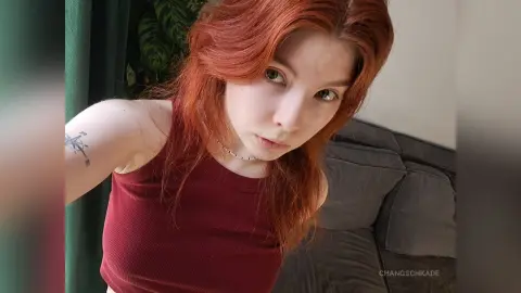 Redheaded woman in a burgundy ribbed tank top posing indoors with a soft, natural mood.
