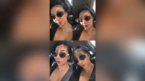 Stylish woman in black top and sunglasses taking a selfie in a car with a confident mood.