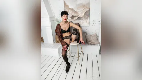 NancyTipped — NancyTipped sits on a white stool wearing black lace lingerie and sheer black stockings.