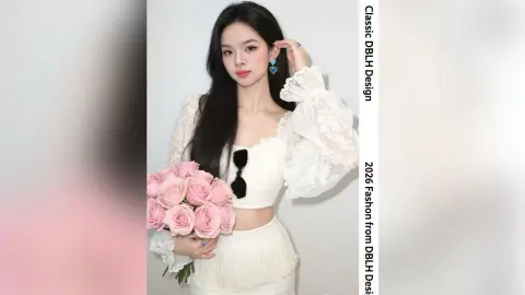 Elegant woman in white lace puff-sleeve crop top holding pink roses in a romantic studio setting.